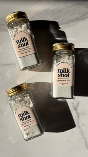 Three bottles of 'milk shot' on a marble surface